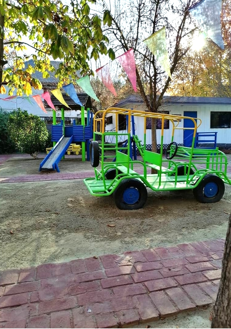 Juegos infantiles del jardín entre árboles